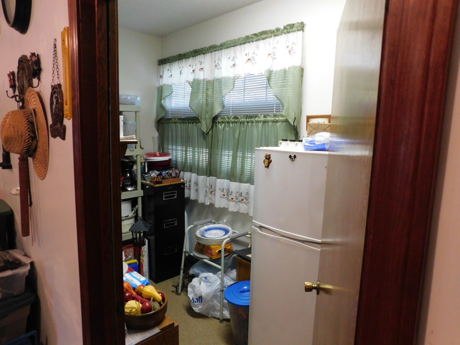 A kitchen with a refrigerator and a bowl of fruit on the counter.
