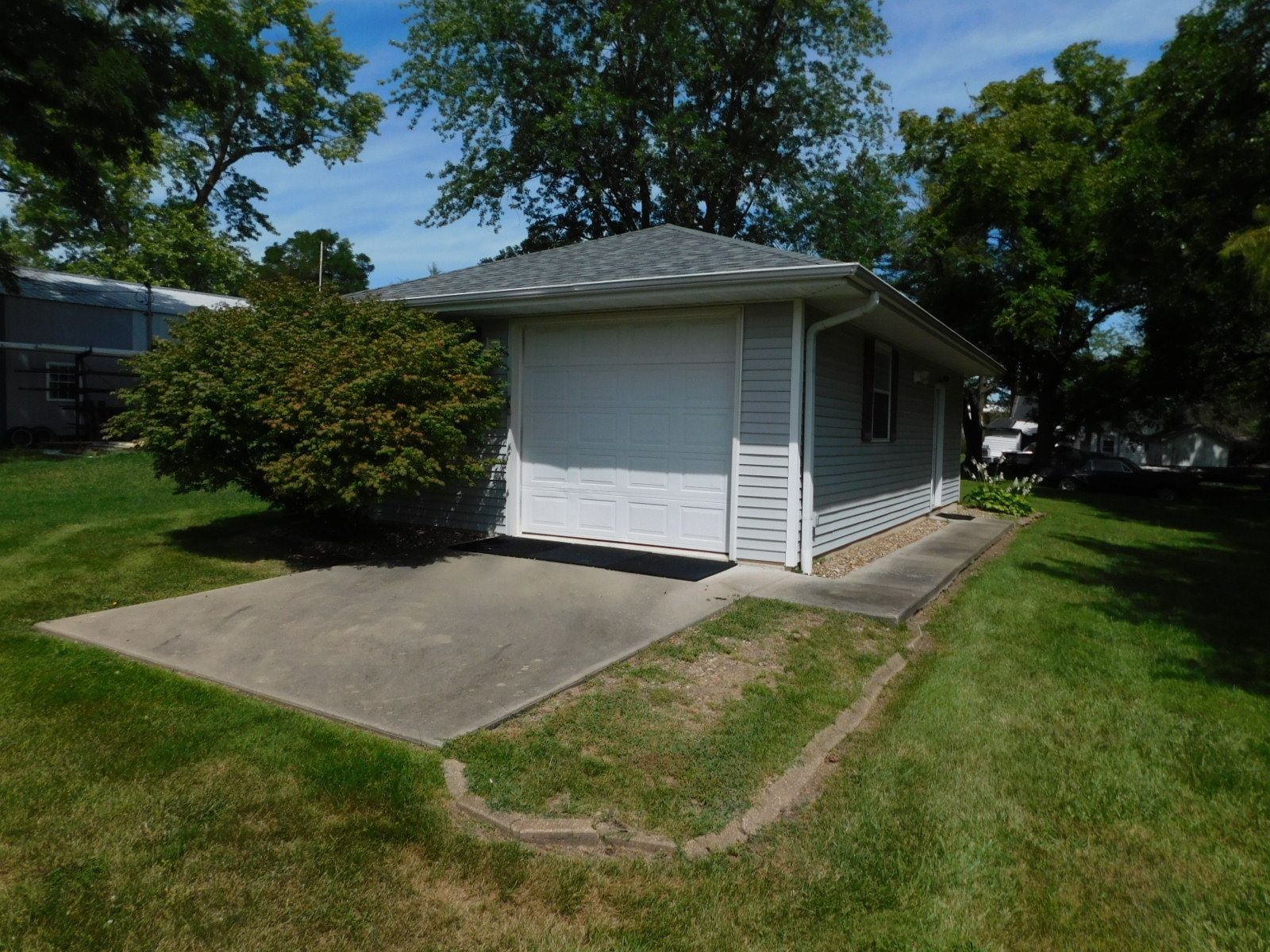 A small white house with a garage in the backyard.