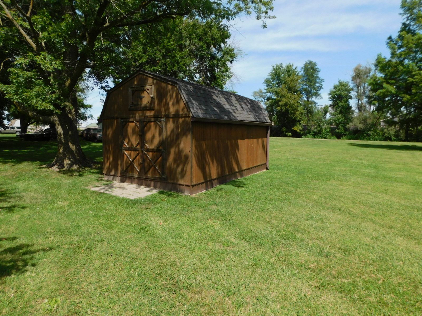 A barn is sitting in the middle of a grassy field.