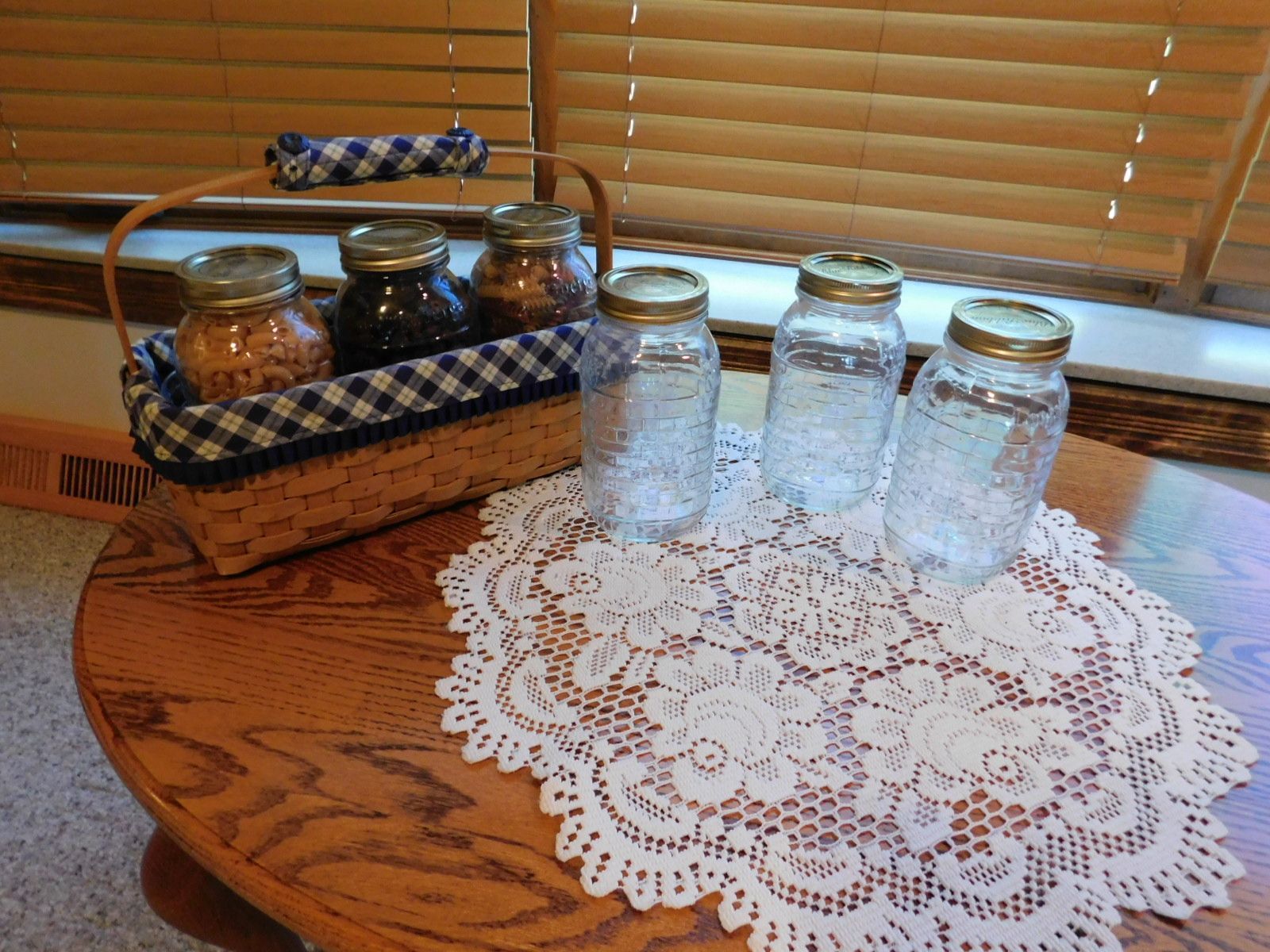 A table with a basket of jars and glasses on it