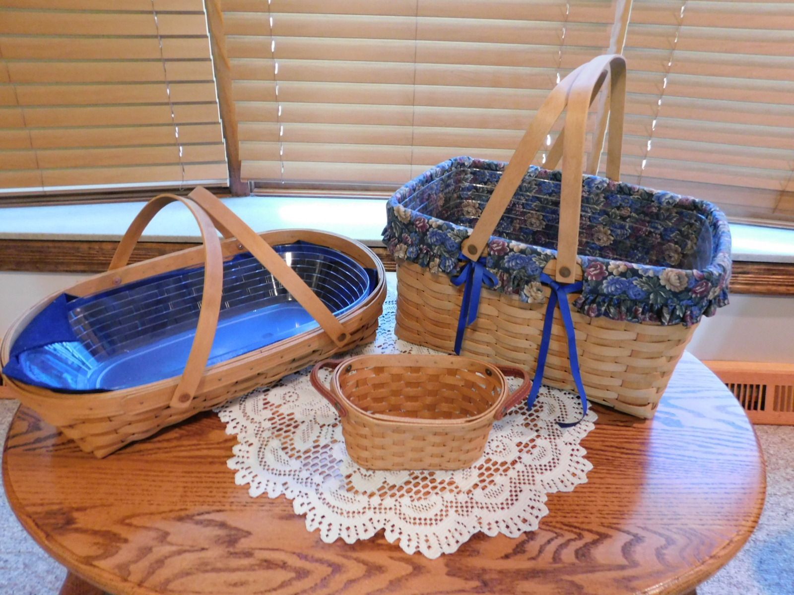 Three baskets are sitting on a wooden table in front of a window