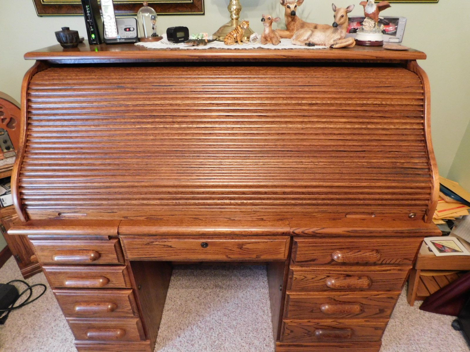 A wooden roll top desk with drawers and a shelf on top.