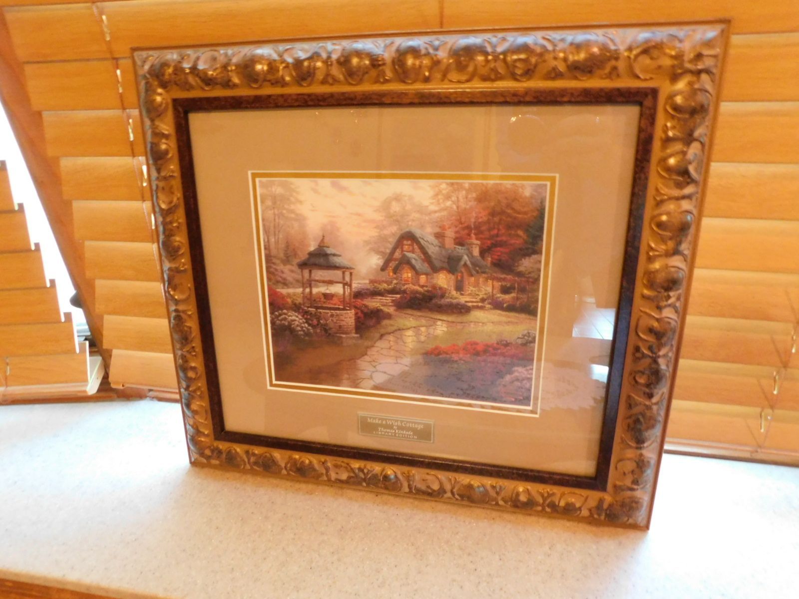 A painting in a gold frame is sitting on a window sill