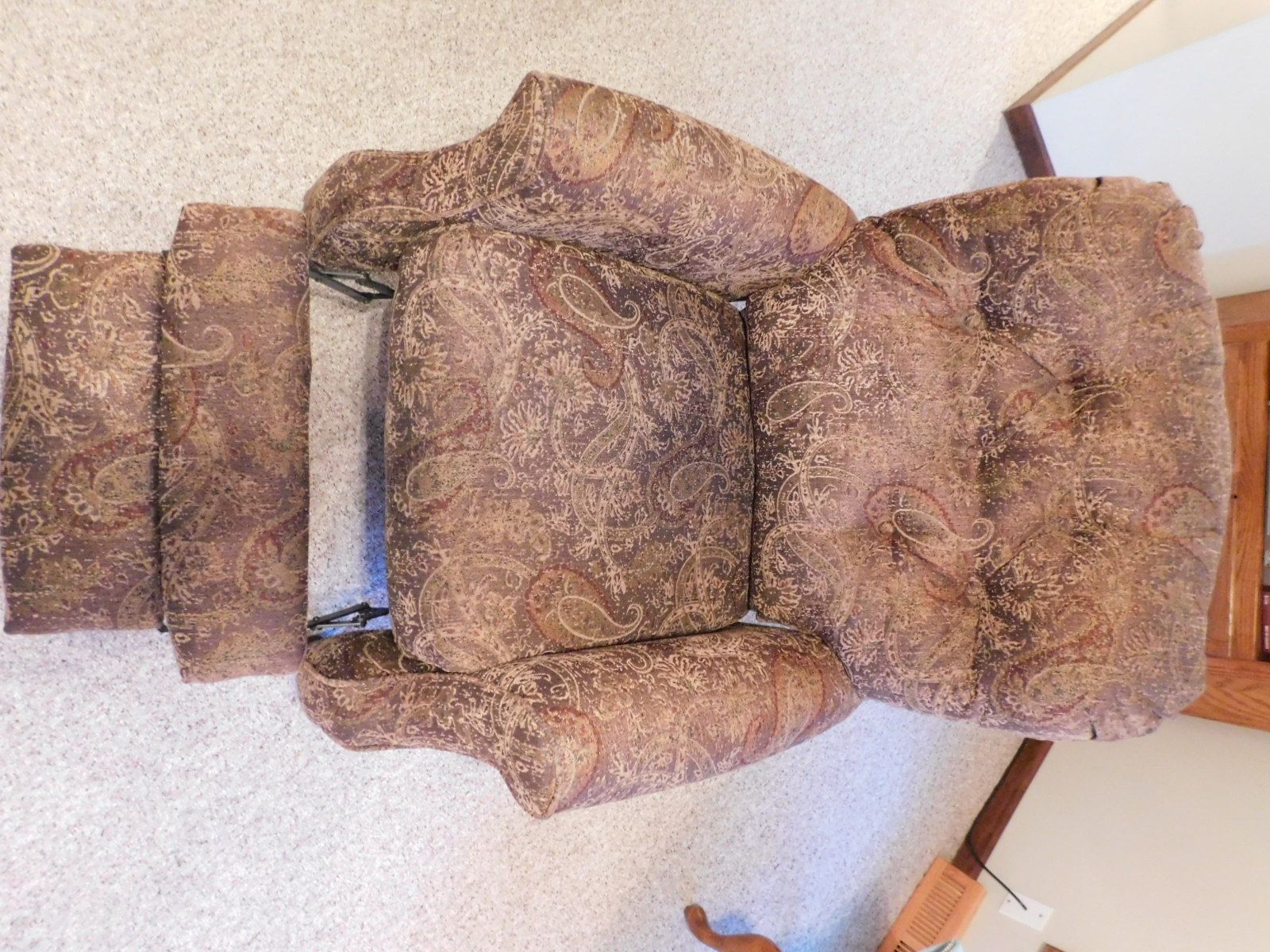A brown recliner is sitting on a white carpet in a living room.