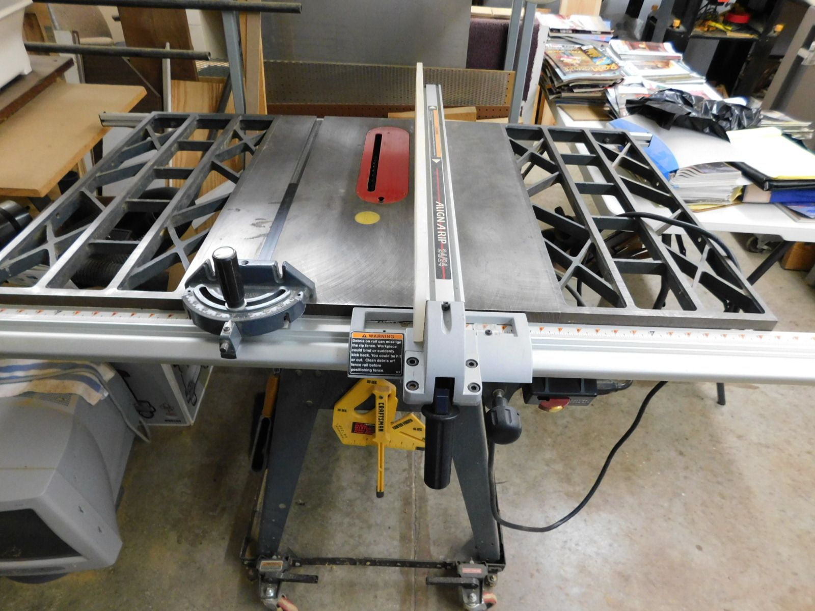 A table saw is sitting on a concrete floor