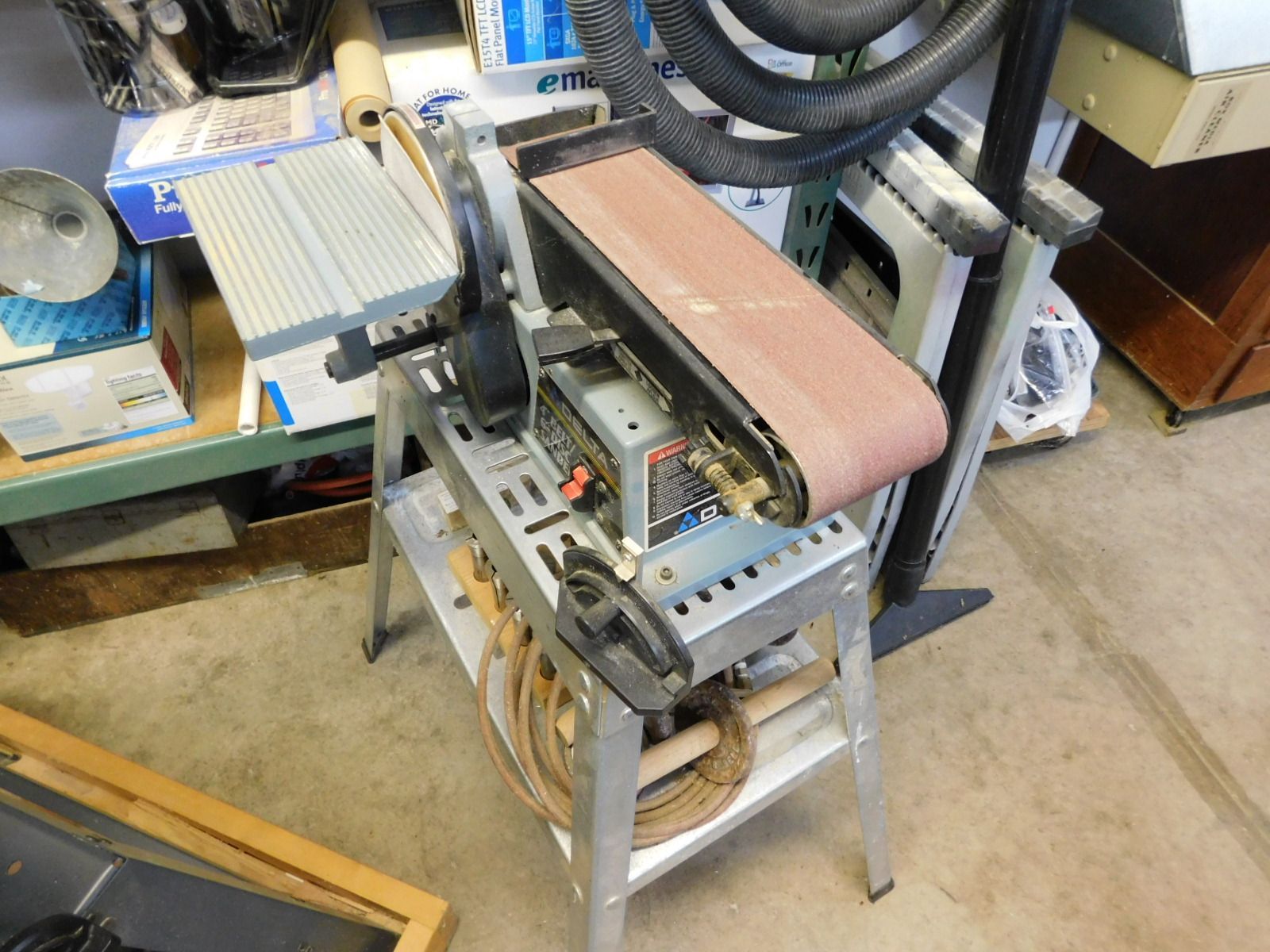 A belt sander is sitting on top of a table in a garage.