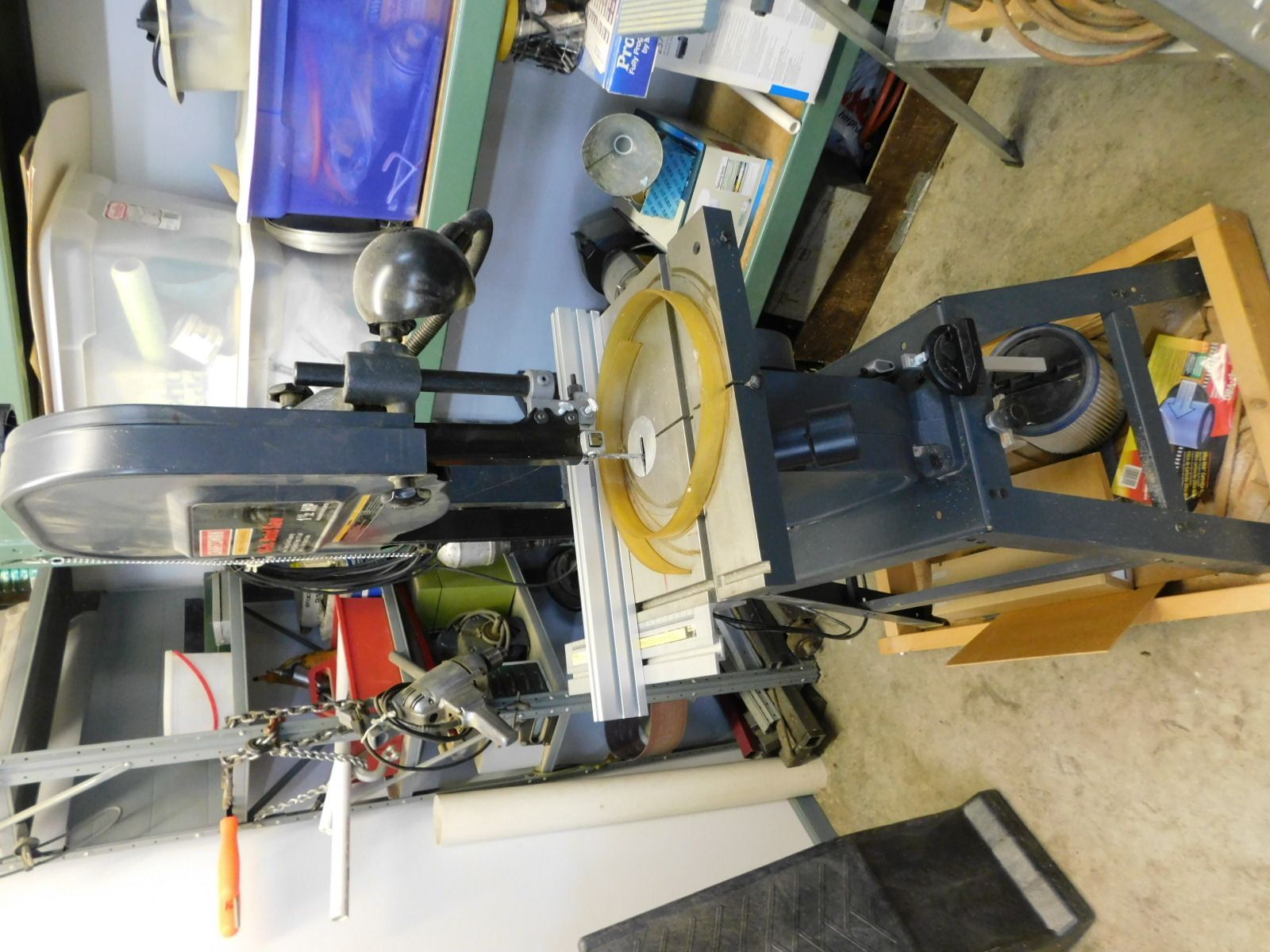 A band saw is sitting on a table in a garage