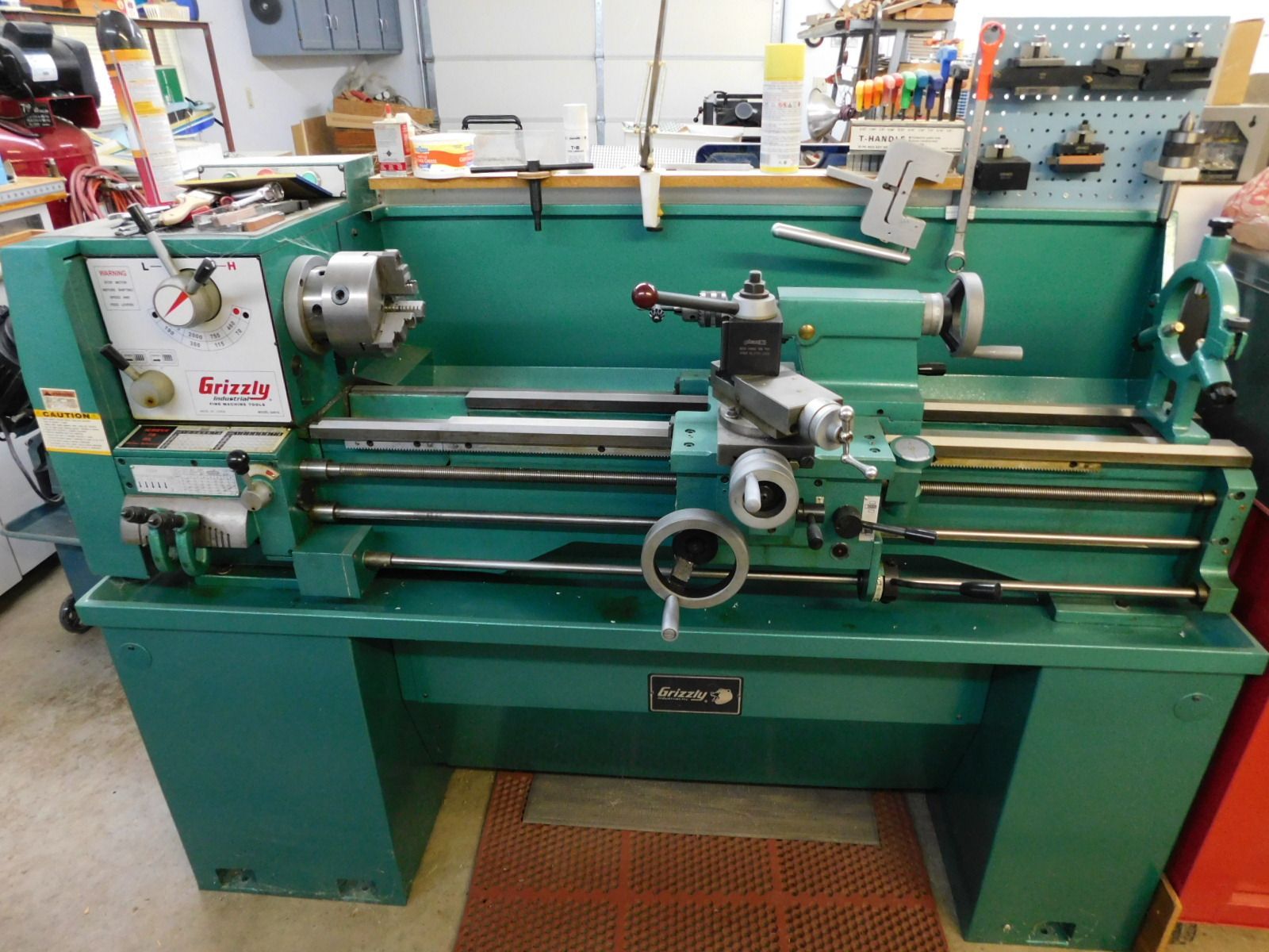 A green lathe is sitting in a workshop.