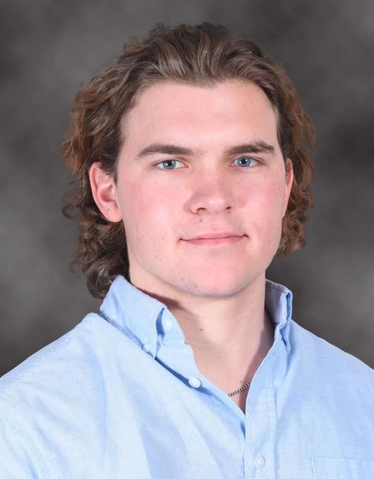 A young man with long hair is wearing a blue shirt.