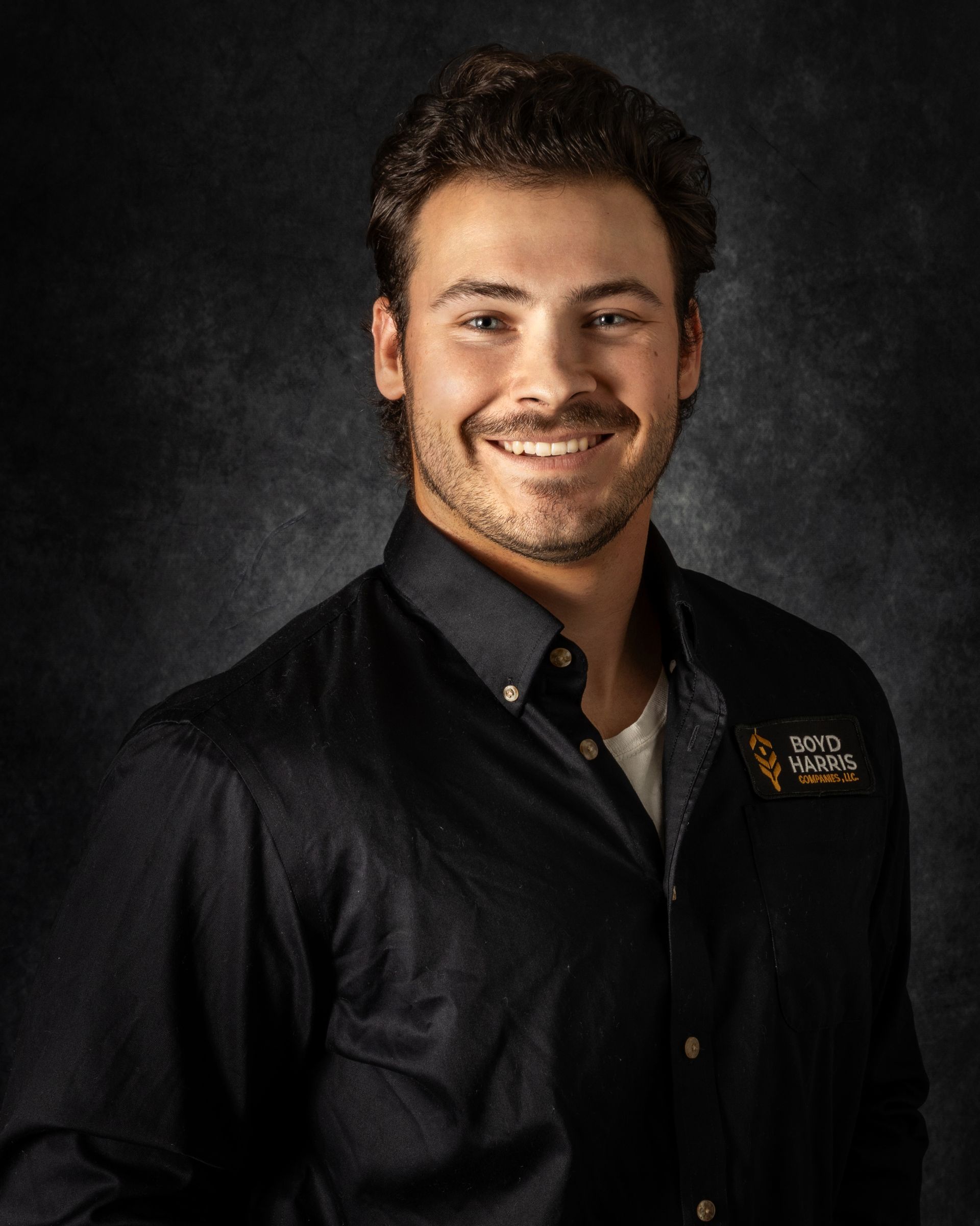 A young man wearing a white polo shirt smiles for the camera
