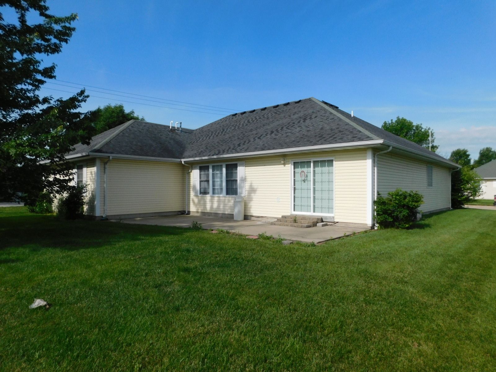 A white house with a gray roof is sitting in the middle of a lush green field.