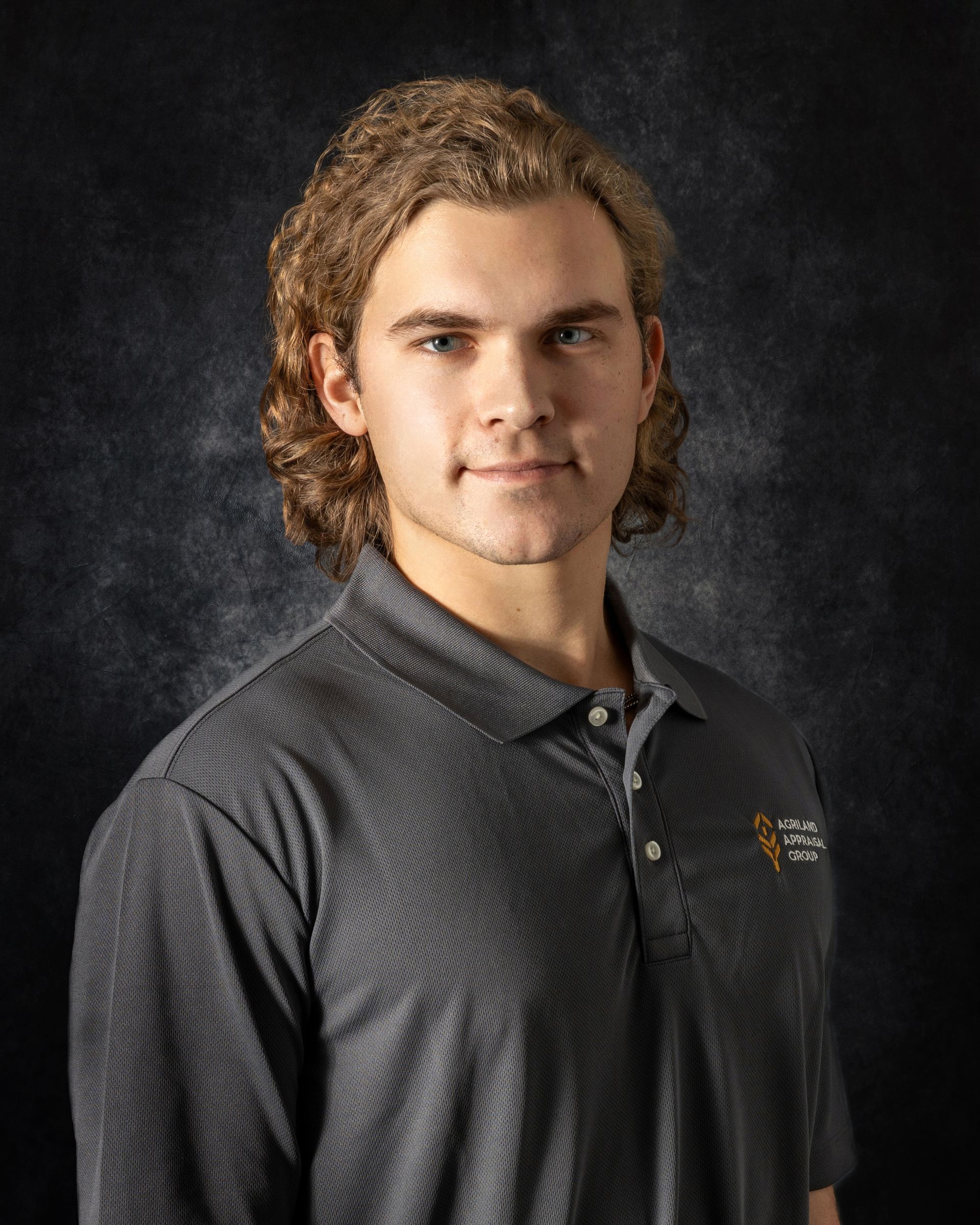 A young man with long hair is wearing a blue shirt.