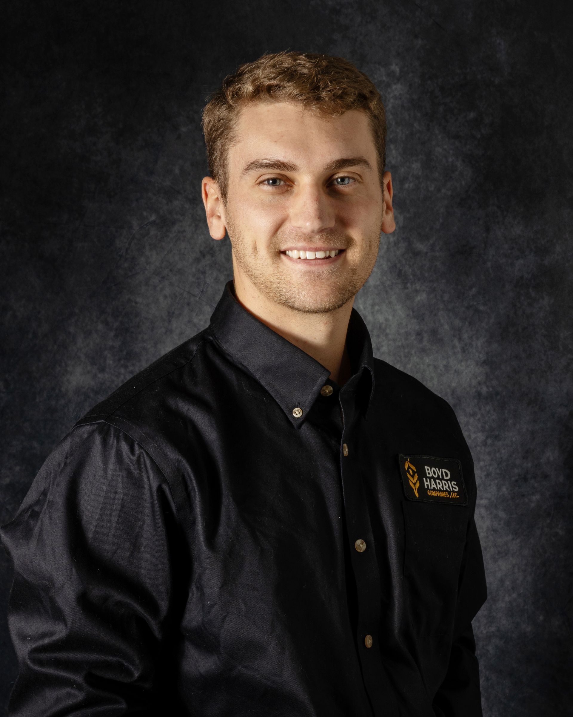 A young man is smiling for a picture in front of a blue background.