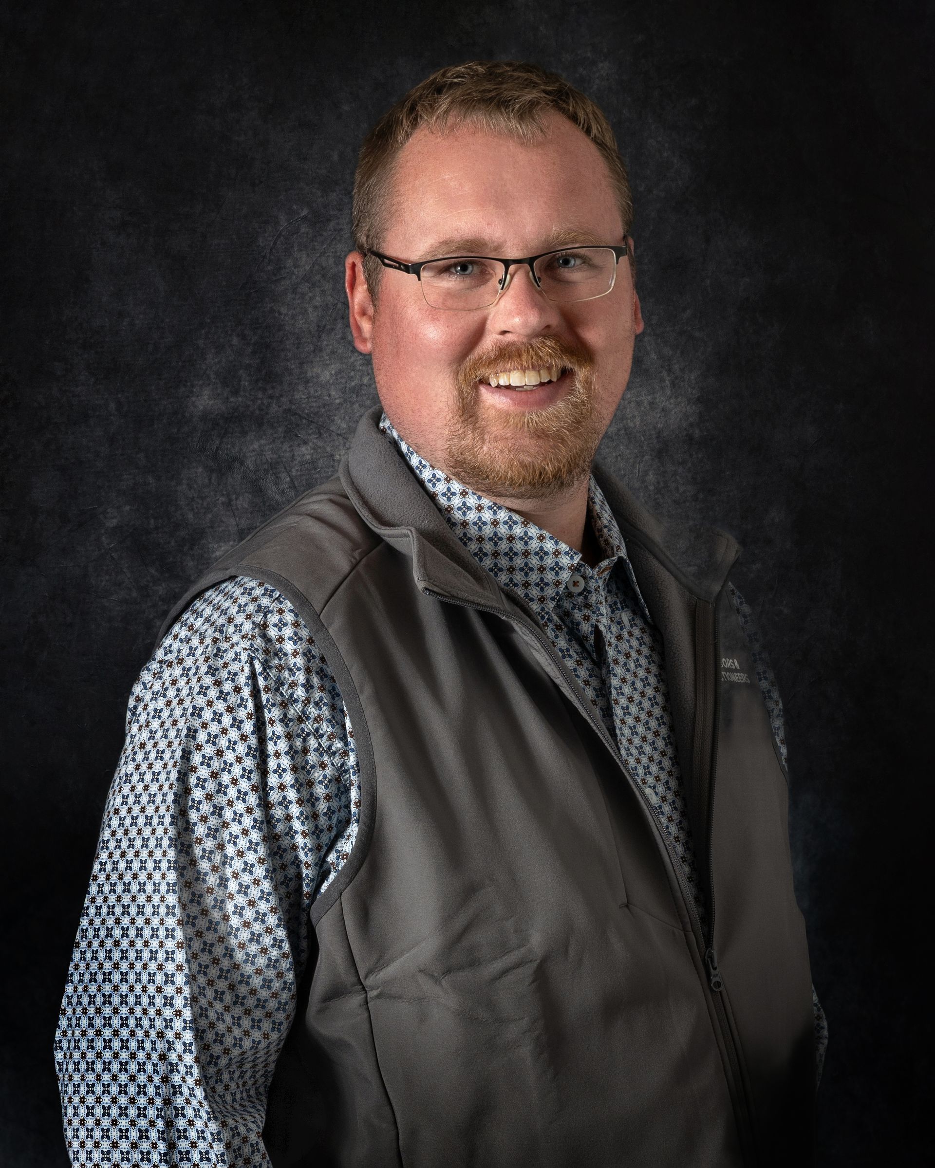 A young man with long hair is wearing a blue shirt.
