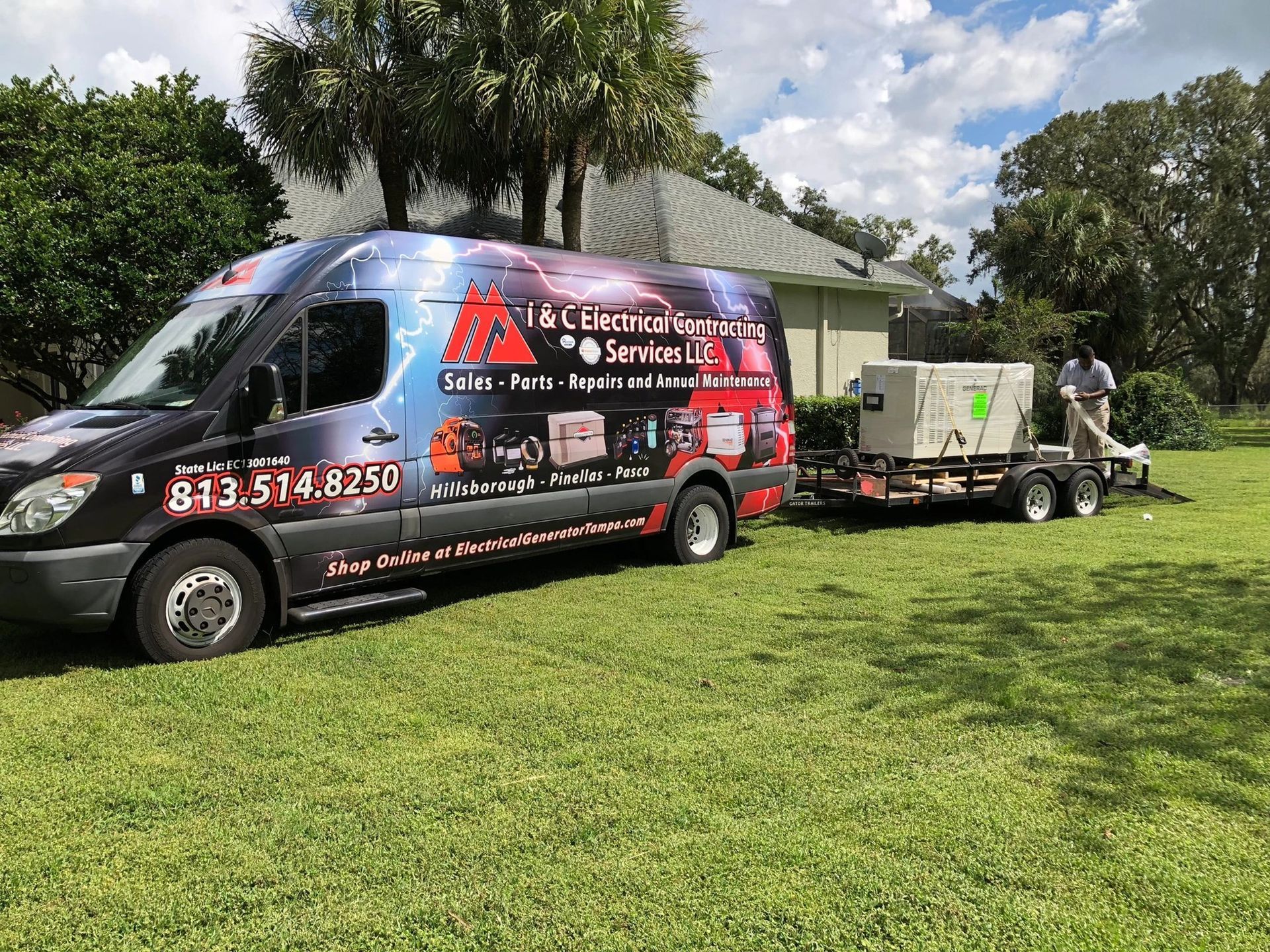 Black van with electrical services logo towing a generator on a trailer in front of a house.