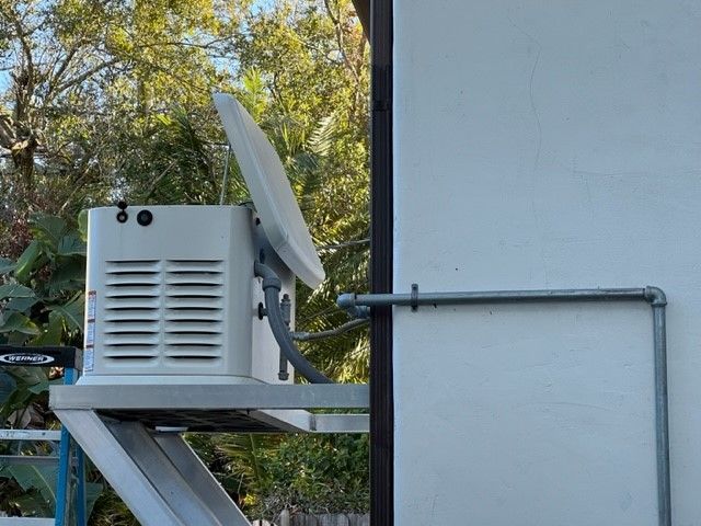 White satellite dish mounted on a box attached to a building's exterior.