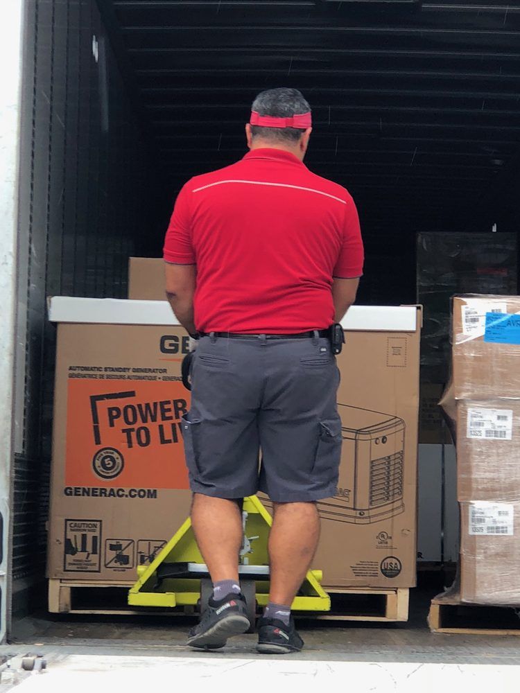 A person in a red shirt and shorts is loading a large box with a 