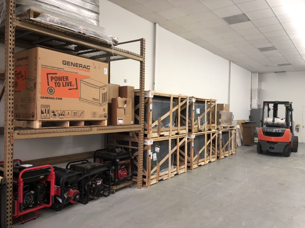 Warehouse with shelves holding generator boxes, crates, and small generators. A forklift is nearby.