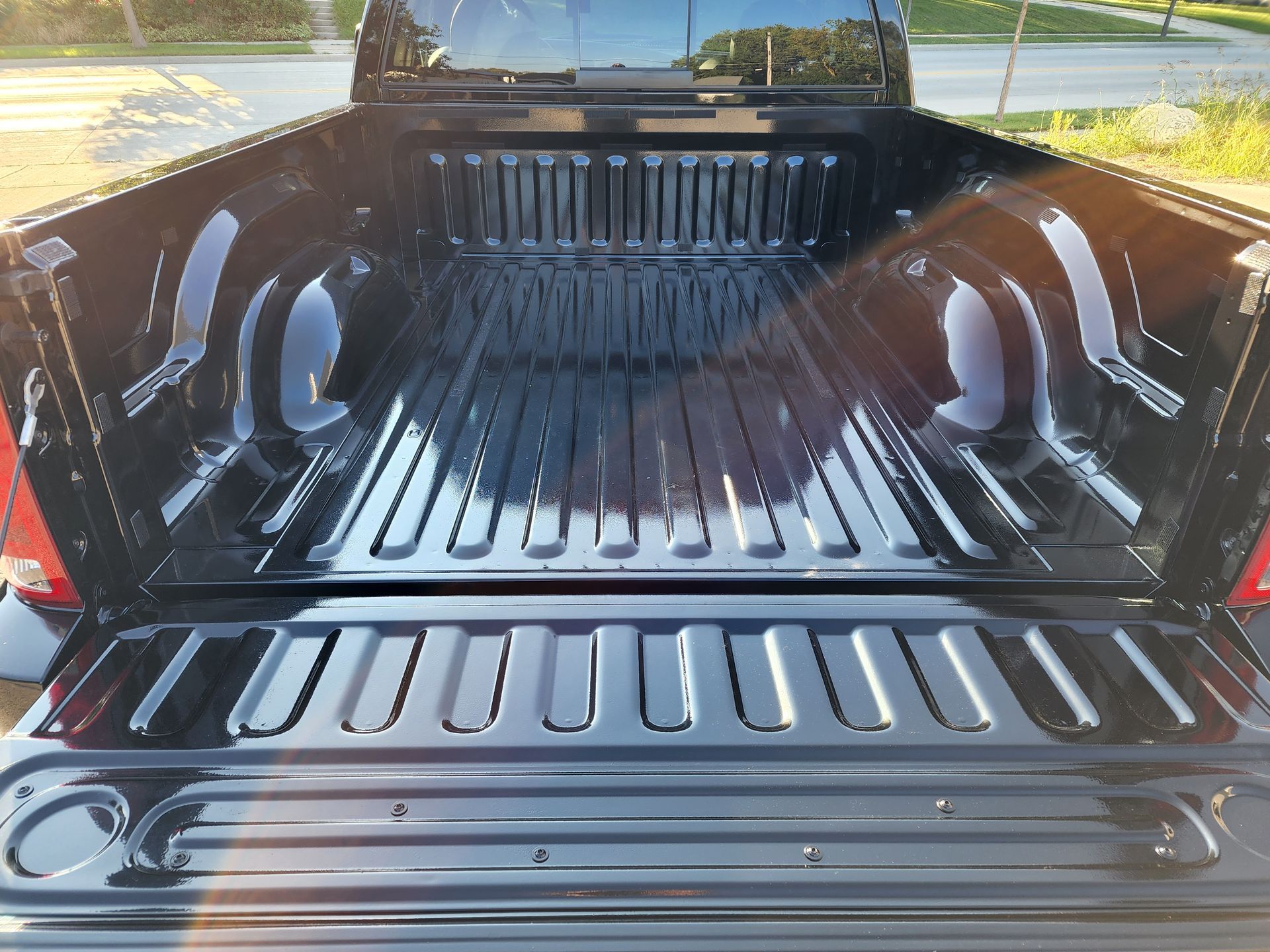 The back of a black truck with the bed open