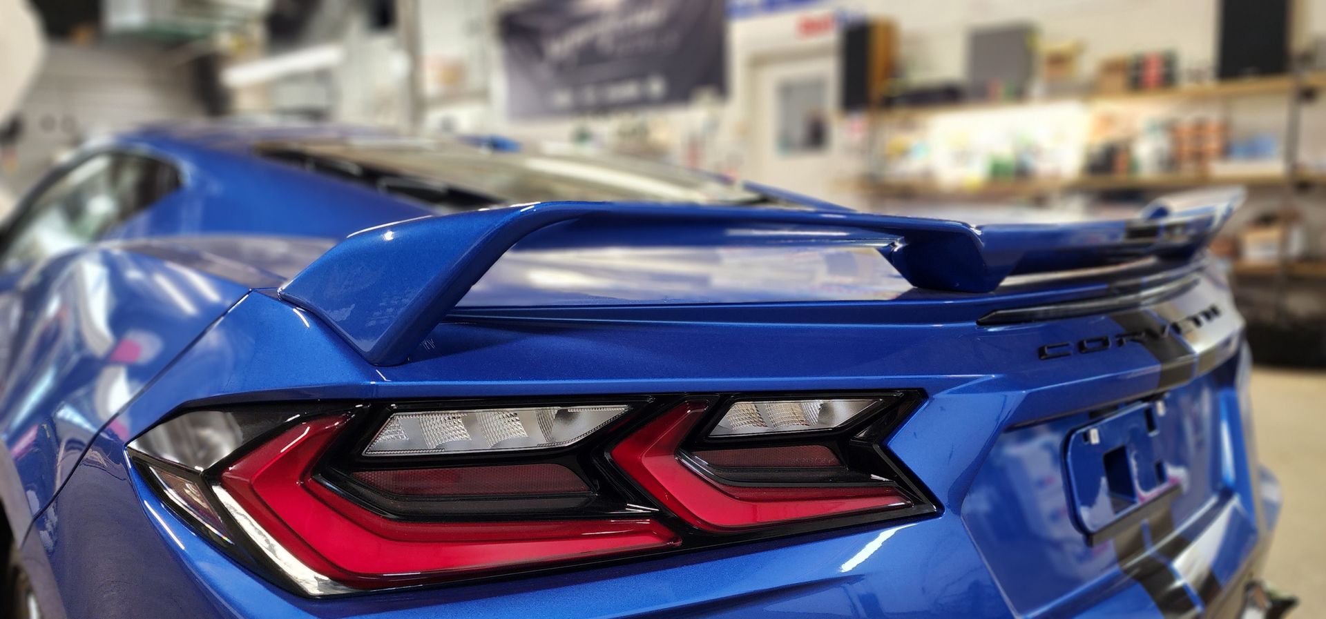 The rear end of a blue corvette is shown in a garage.