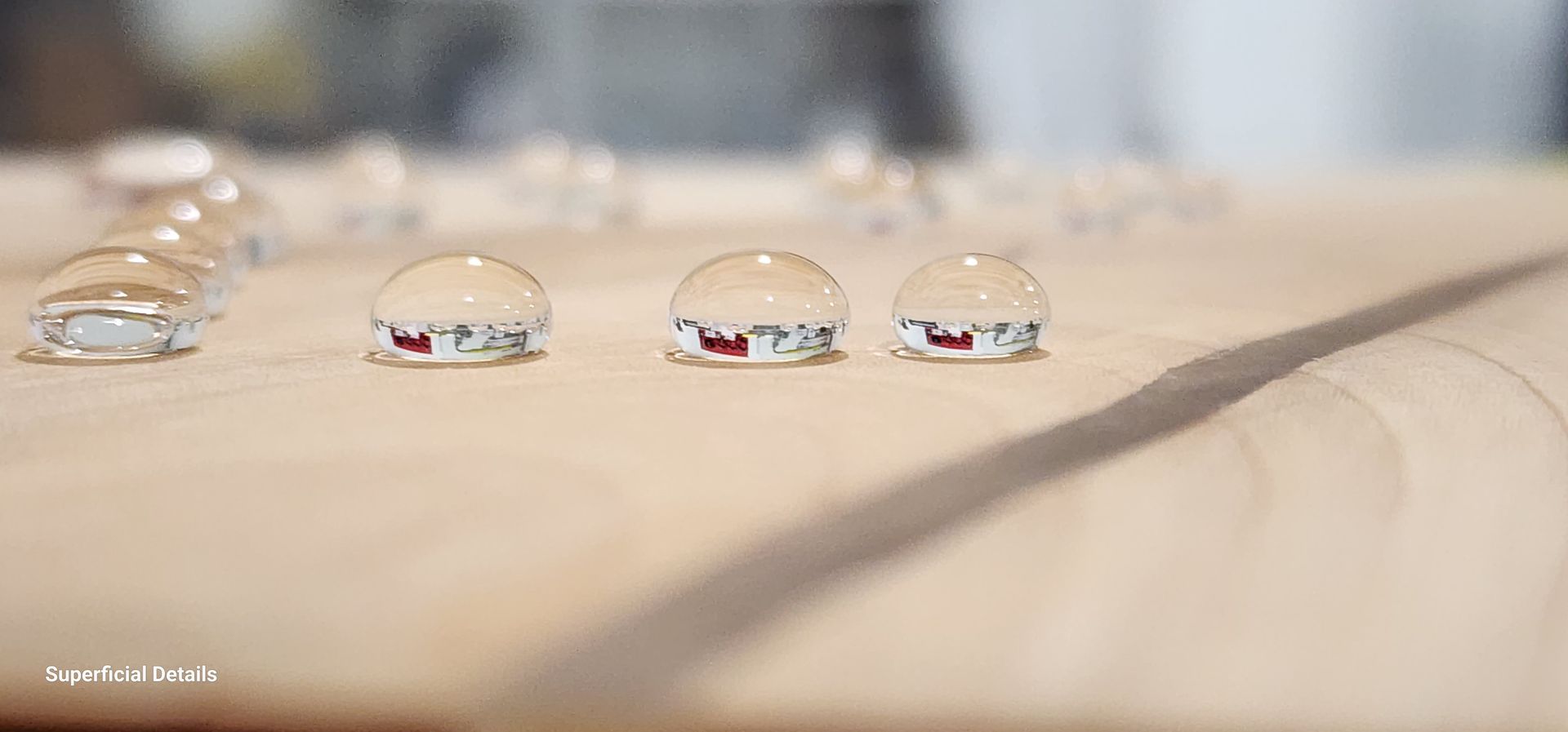 A row of water drops on a wooden surface.