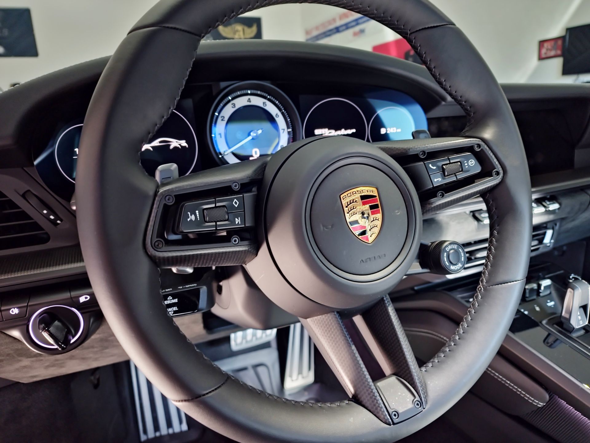 A close up of a porsche steering wheel and dashboard