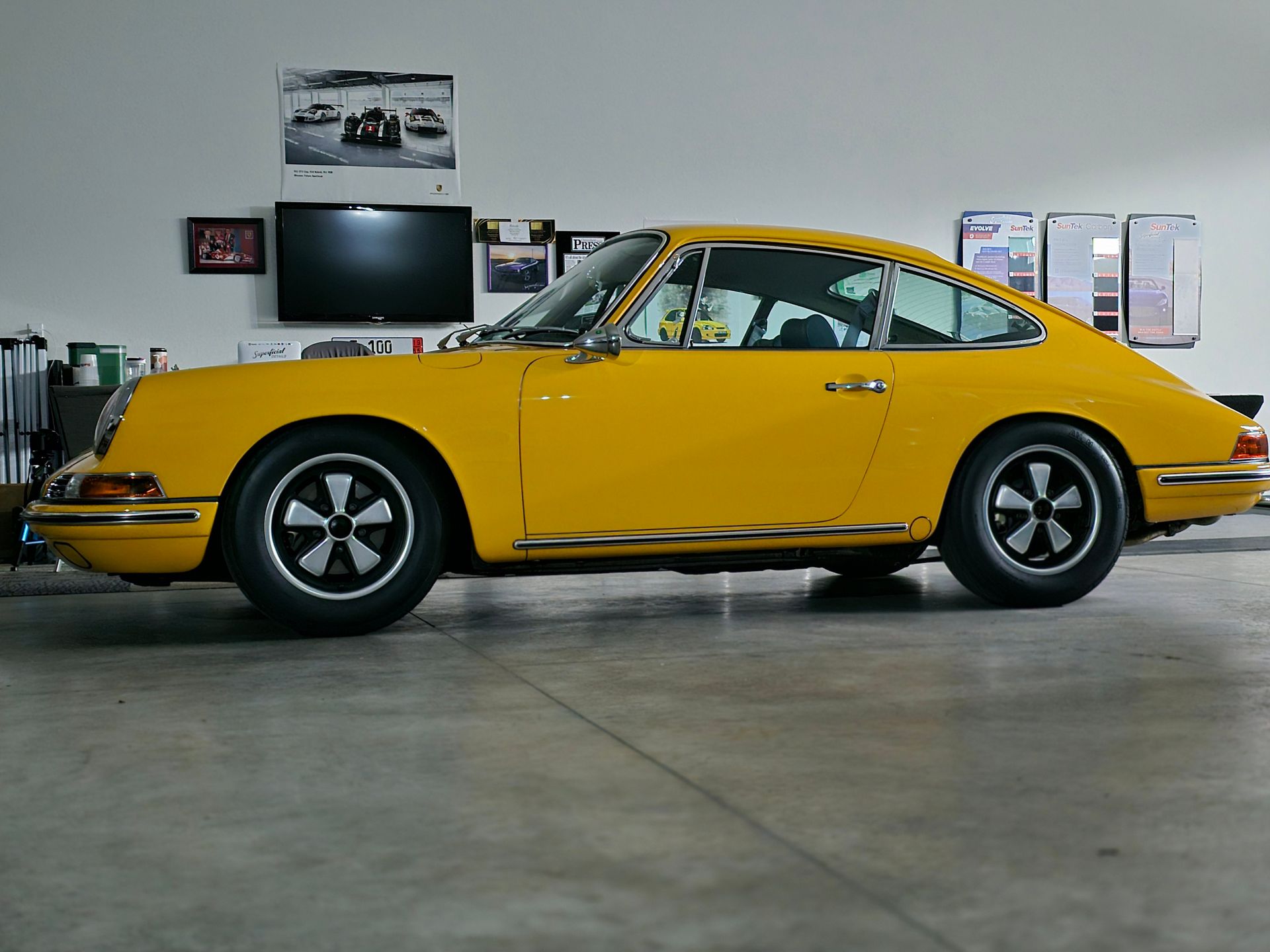 A yellow porsche is parked in a garage.