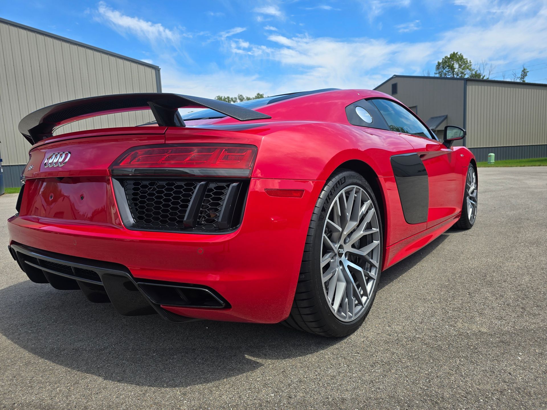 A red audi r8 is parked on the side of the road in front of a building.
