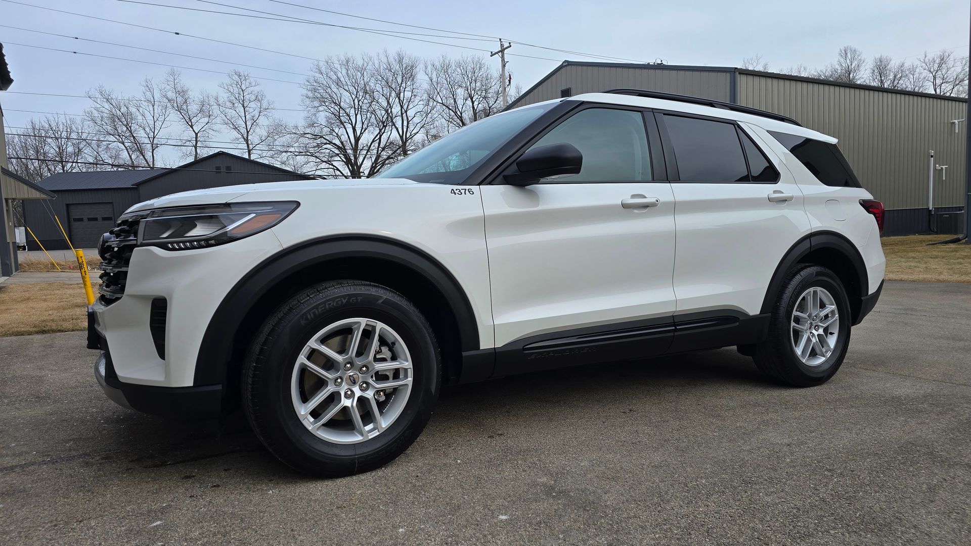 A white Ford Explorer parked on an asphalt lot outdoors on a cloudy day.