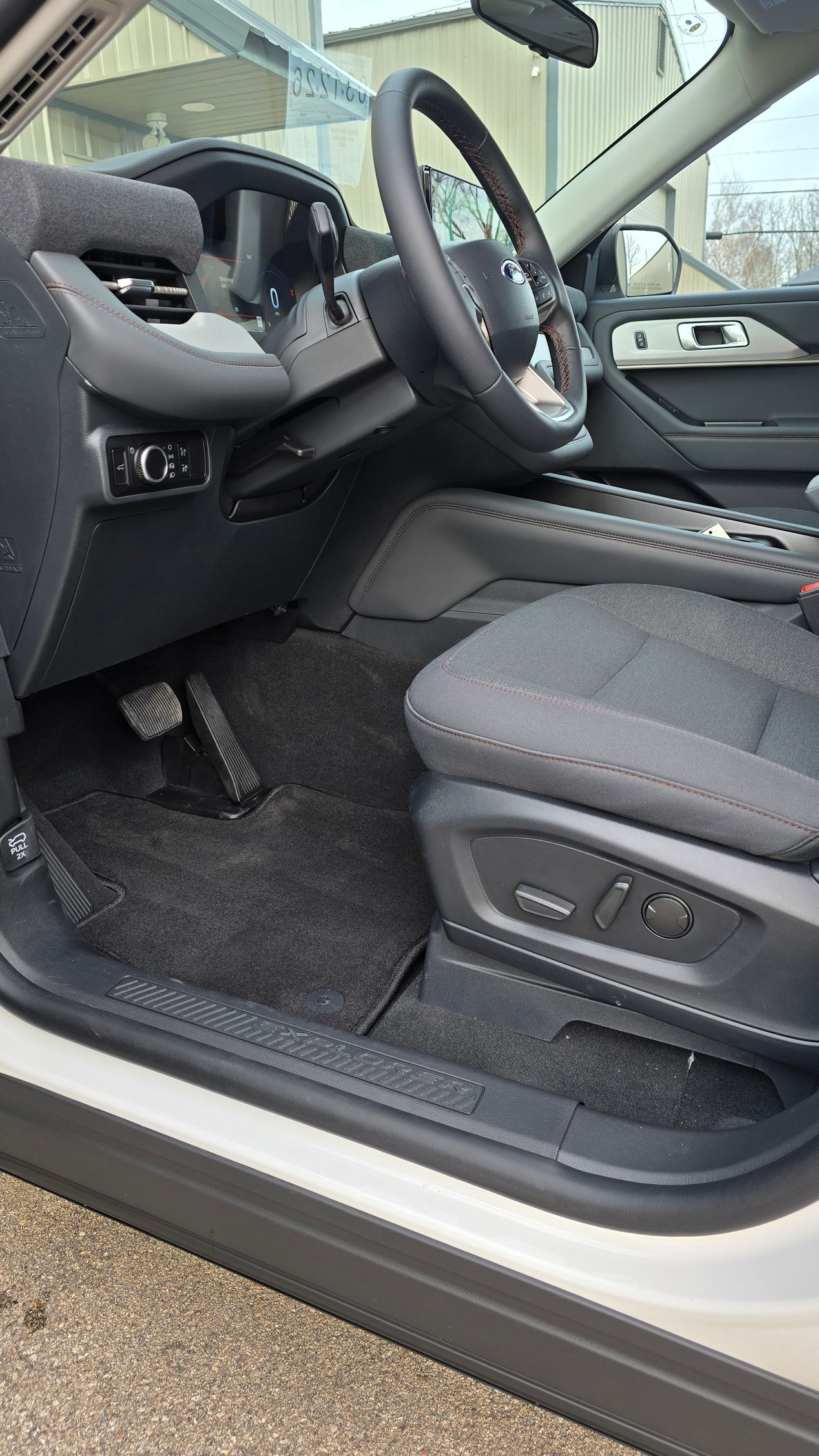 Interior view of a modern vehicle's front cabin, showing the driver's side floor, seat, and steering wheel.
