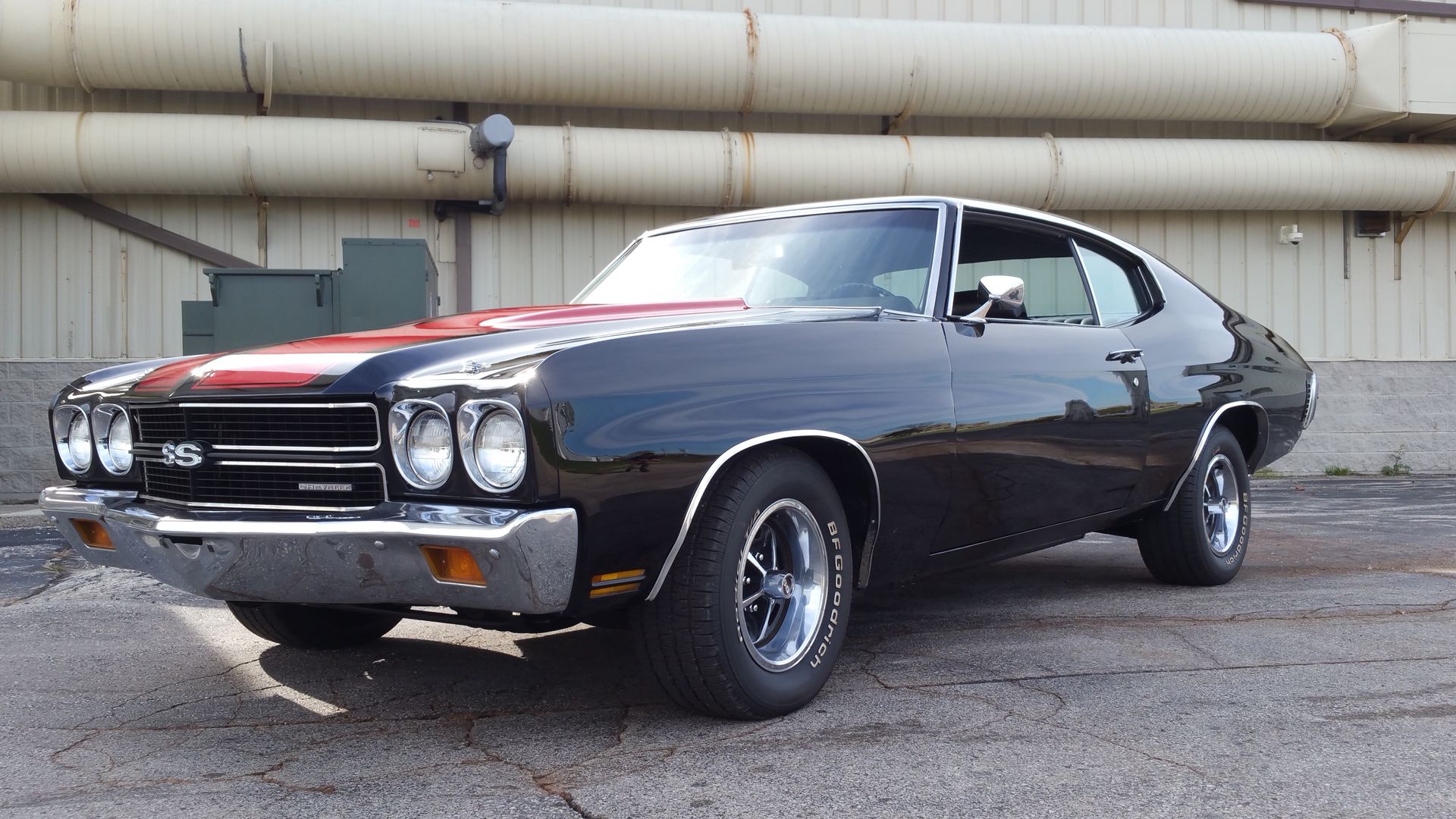 Black 1970 Chevrolet Chevelle SS, parked outside a building, with red racing stripes on the hood.