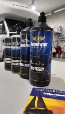 ARK Marine product range display: bottles of marine cleaning and detailing products on a table, with a catalog, and a boat in the background.