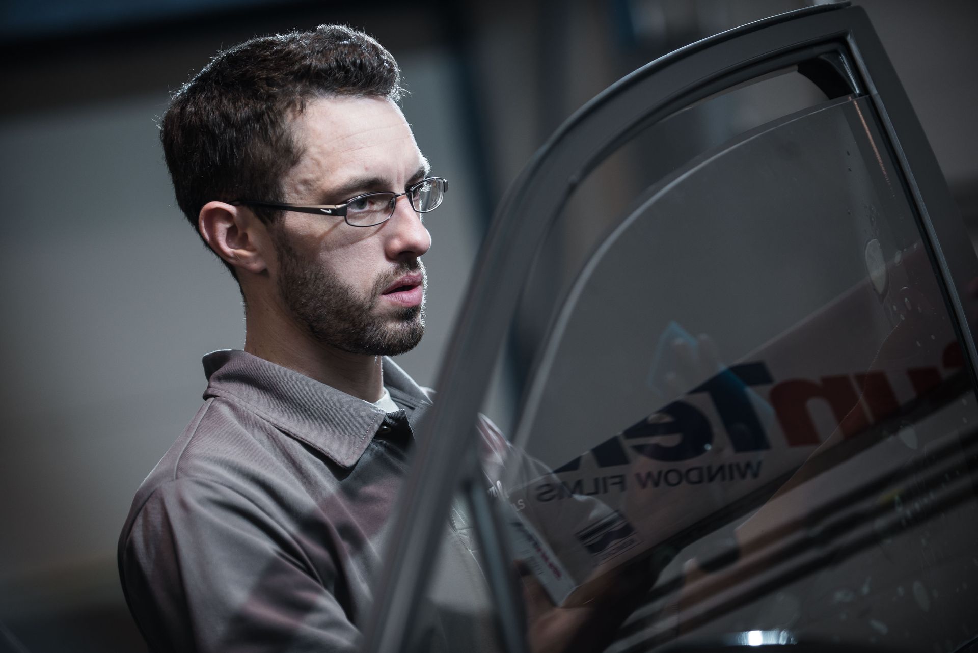 man tinting window on car
