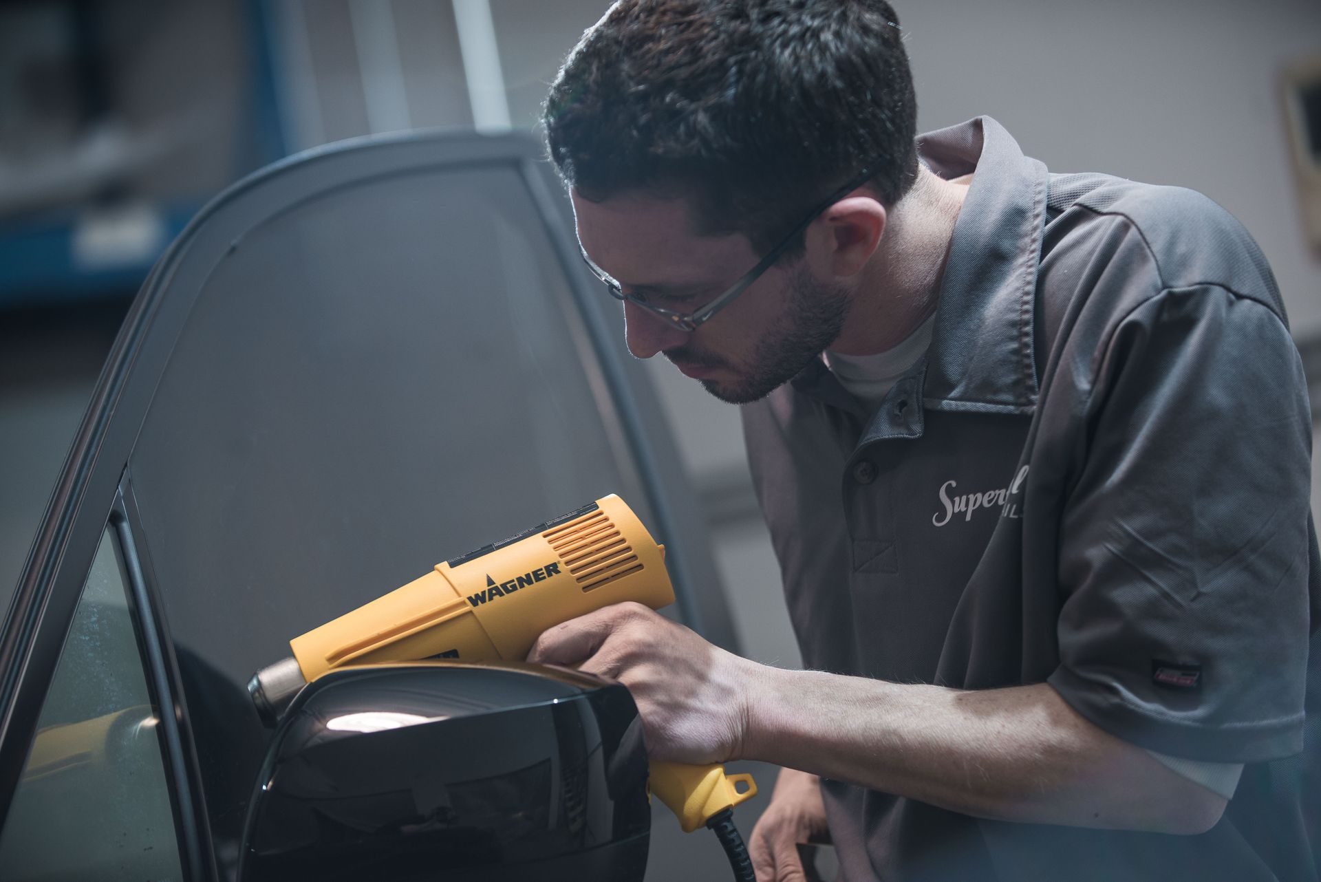 A man is working on a car with a yellow tool.