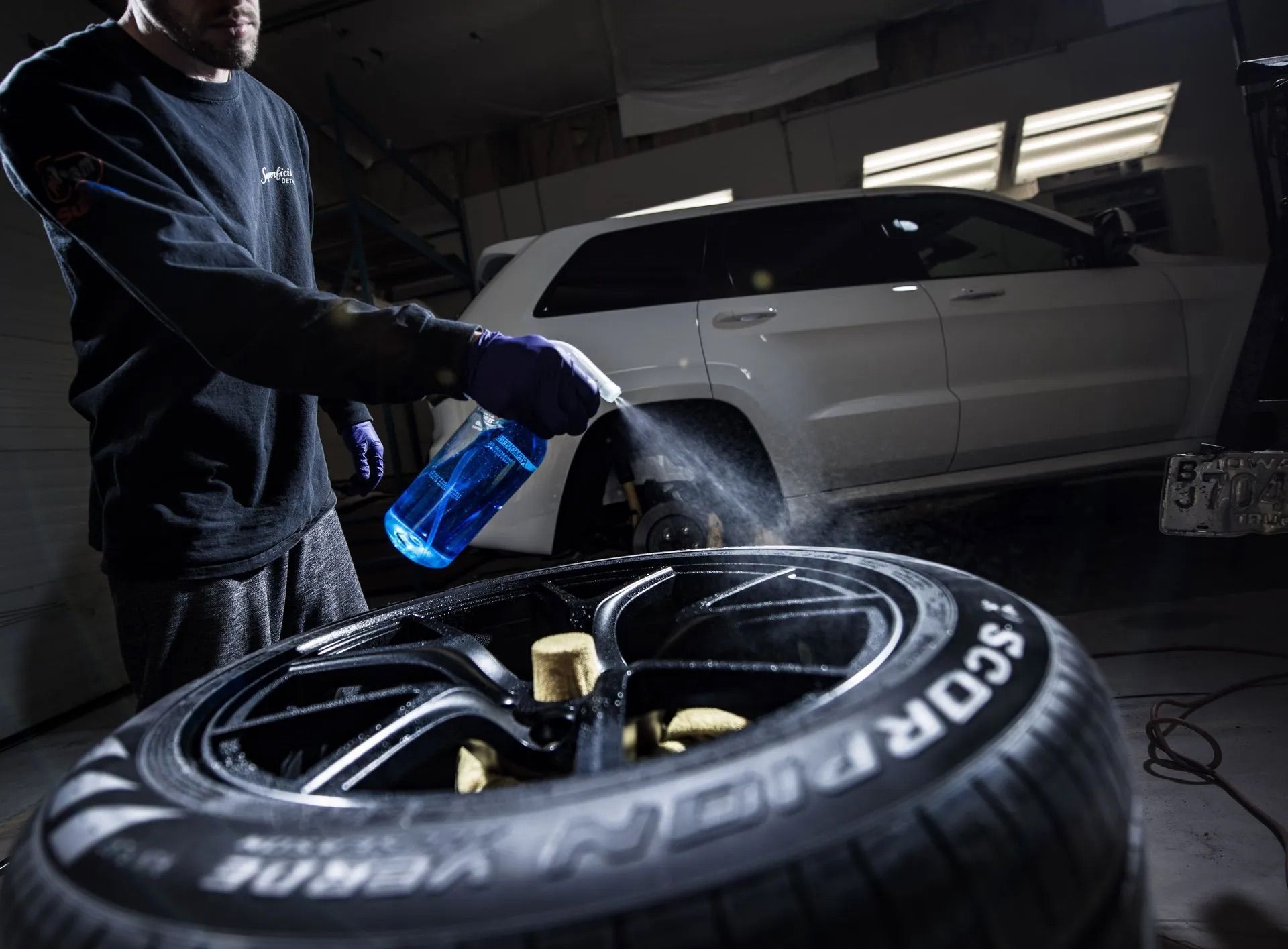 A man is spraying a tire with a spray bottle.