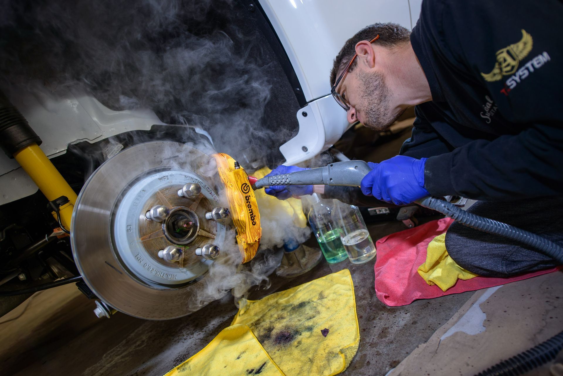 A man is working on a car with a yellow tool.