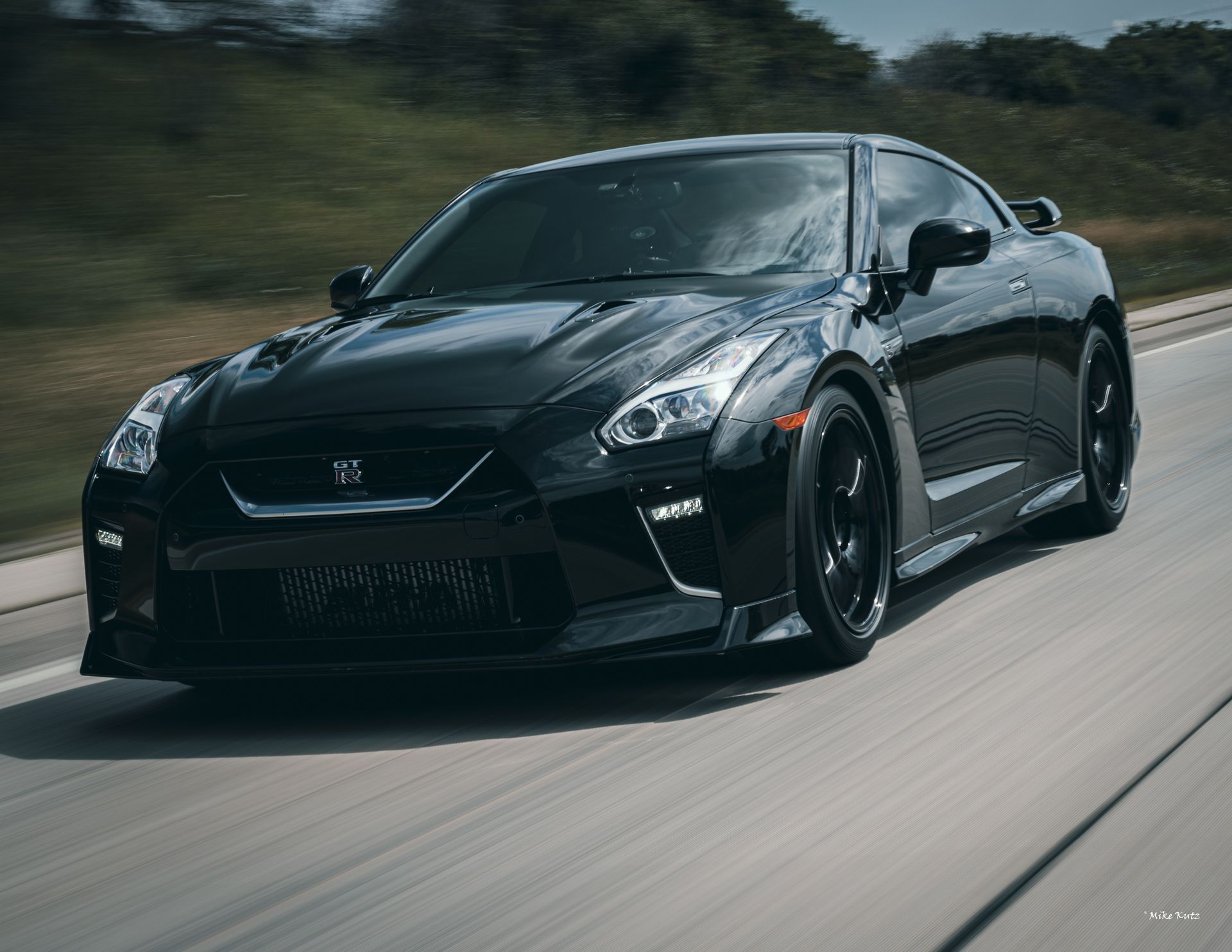 A black sports car is driving down a highway.