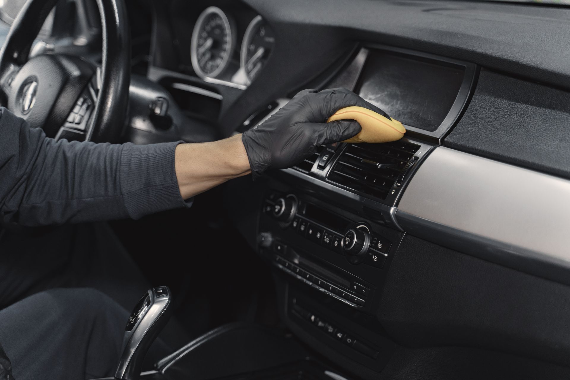 A person is cleaning the dashboard of a car with a sponge.