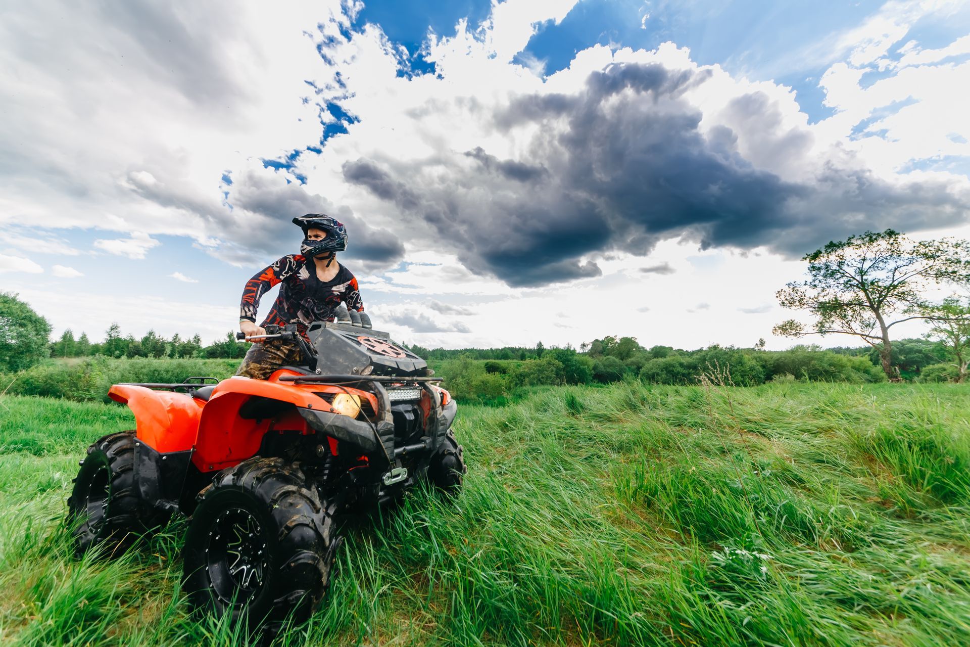 A man is riding an atv through a grassy field.
