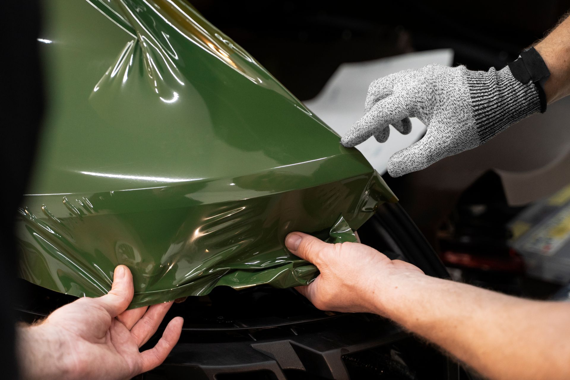 a person is wrapping a car in green plastic .