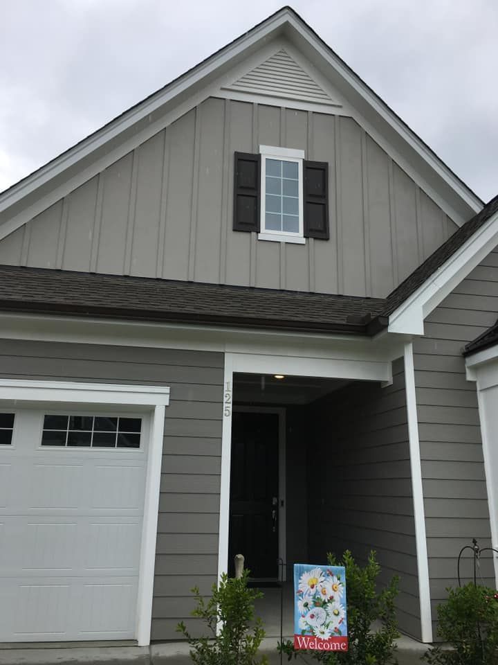 Gray house exterior with garage and front porch, featuring white trim and black shutters