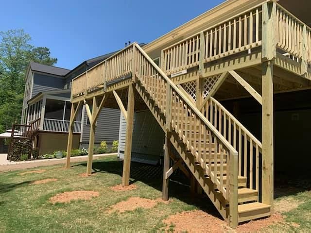 Wooden elevated deck with stairs attached to a house in a grassy backyard