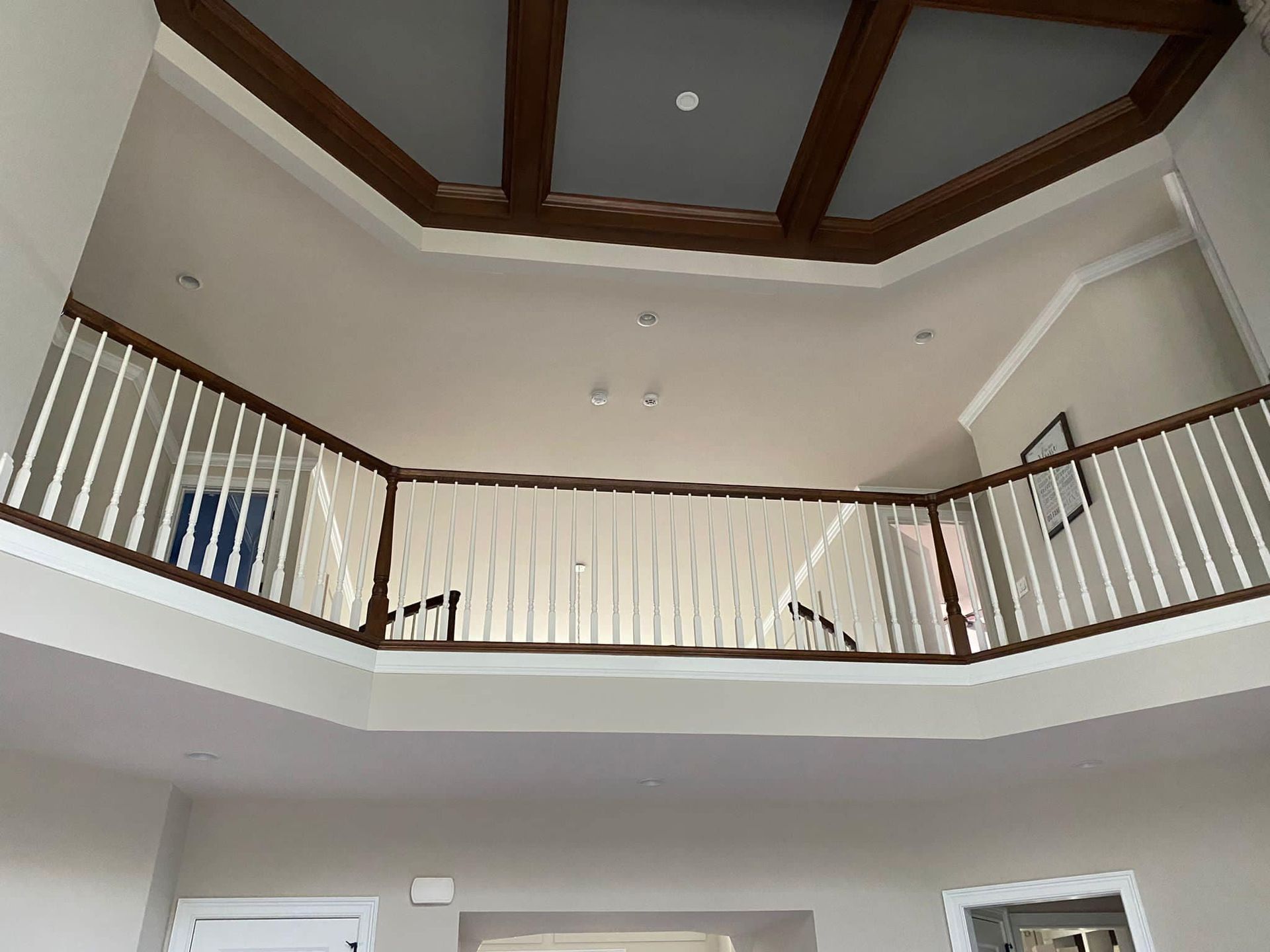 Interior foyer with vaulted ceiling, wood trim, and an upper balcony railing.