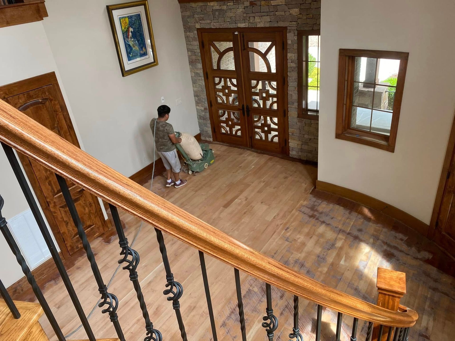 Wooden staircase landing with a seated person, glass double doors, and a windowed entryway