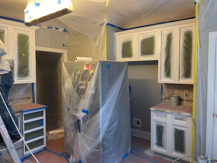 Kitchen under renovation, with cabinets covered in plastic and appliances wrapped in protective sheeting.