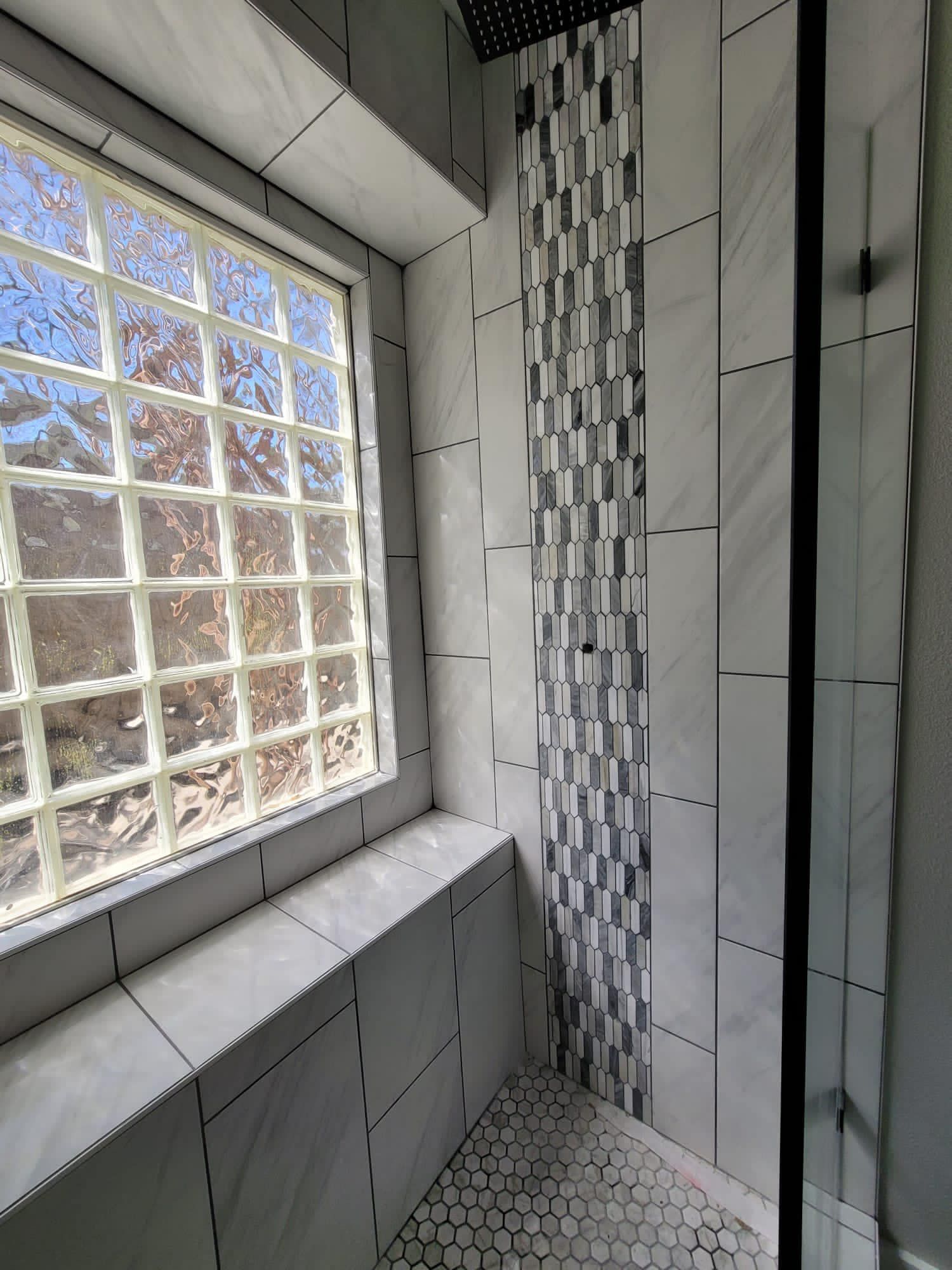 Small tiled bathroom corner with a window and white grout.