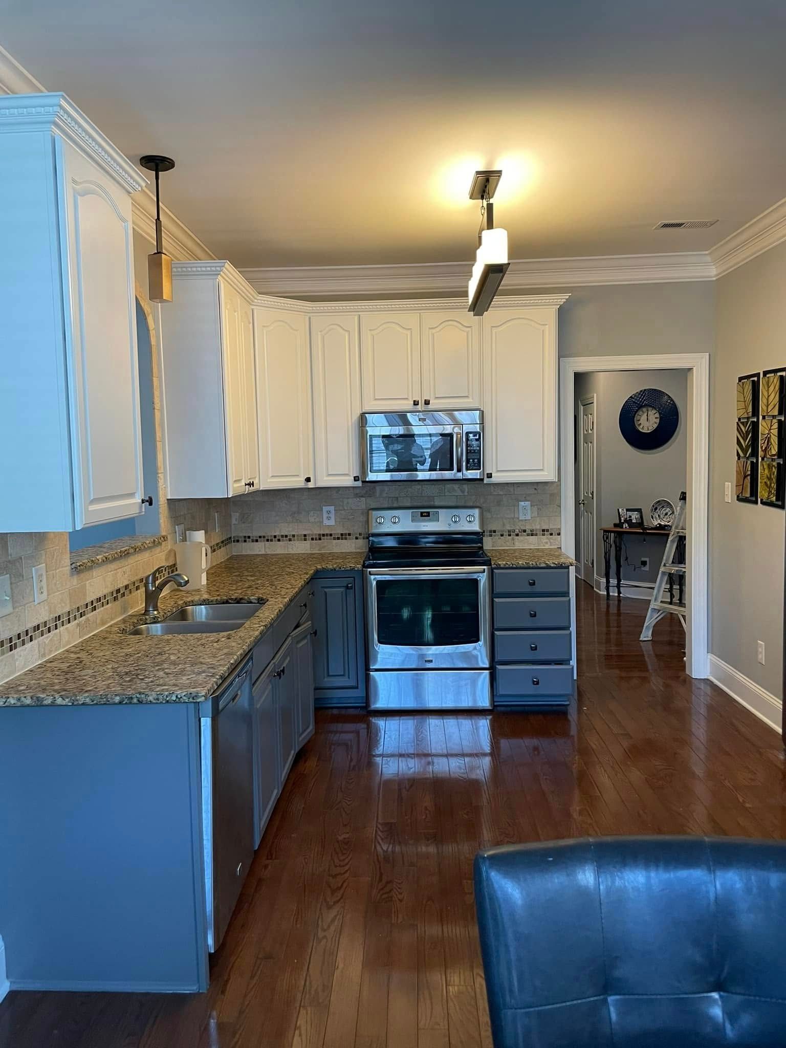 Bright kitchen with white cabinets, granite counters, stainless stove, and hardwood floors.