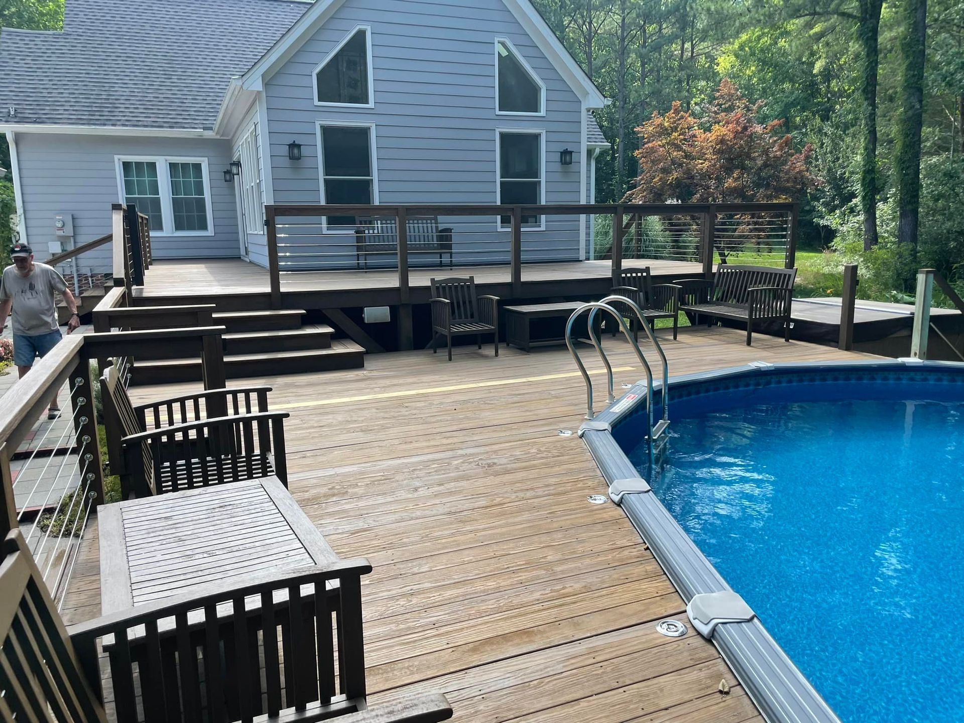 Backyard deck with pool, lounge chairs, and a house in the background