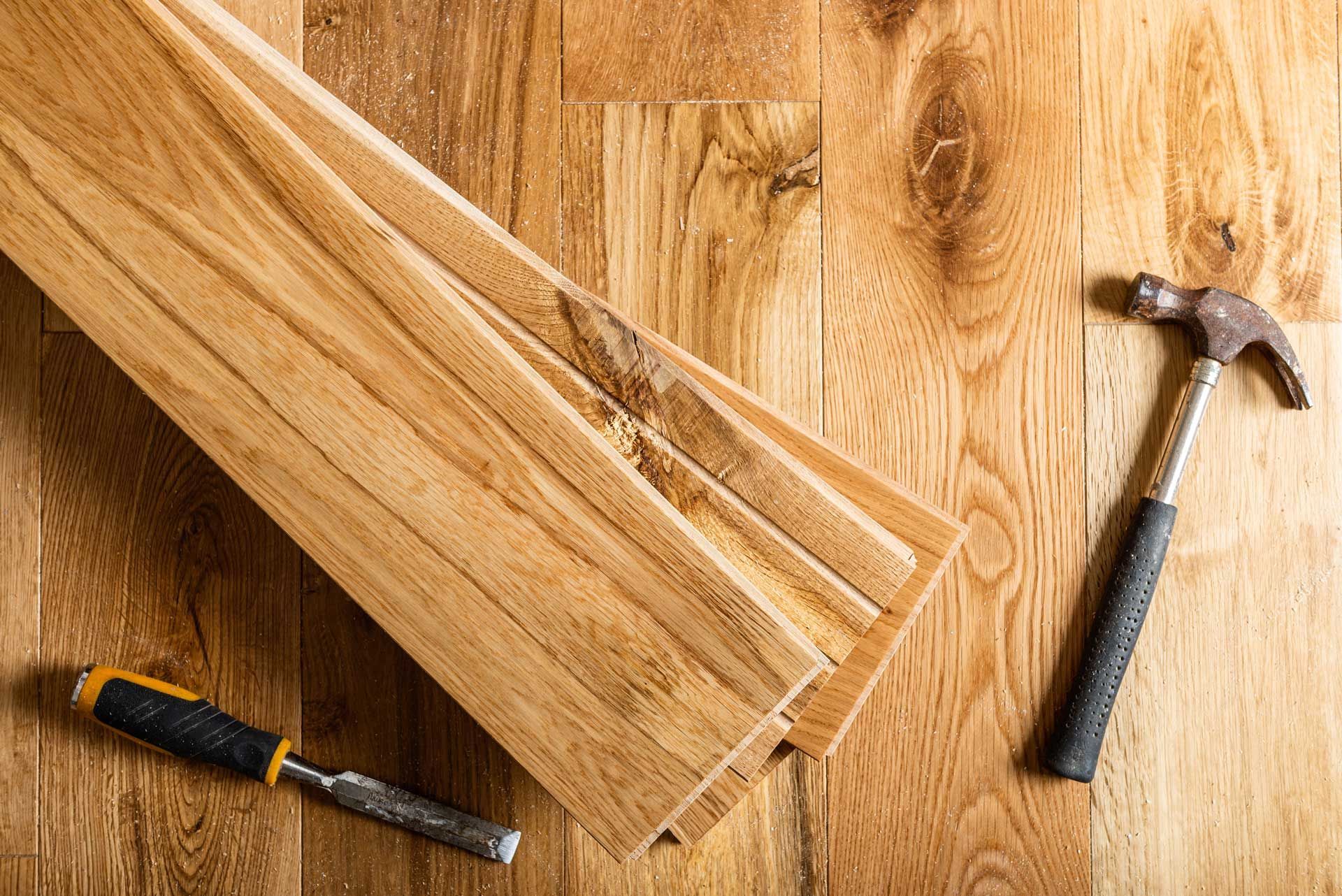 Wooden planks, a screwdriver, and a hammer on a hardwood floor
