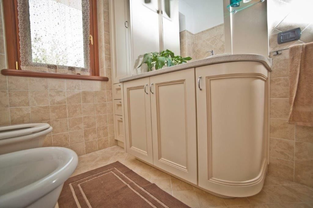 Piccolo bagno piastrellato di beige con mobiletto sottolavabo su misura